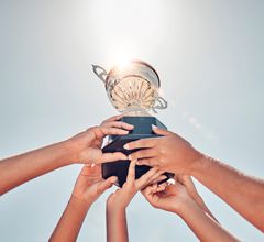 trophy cup being held high by 6 female hands
