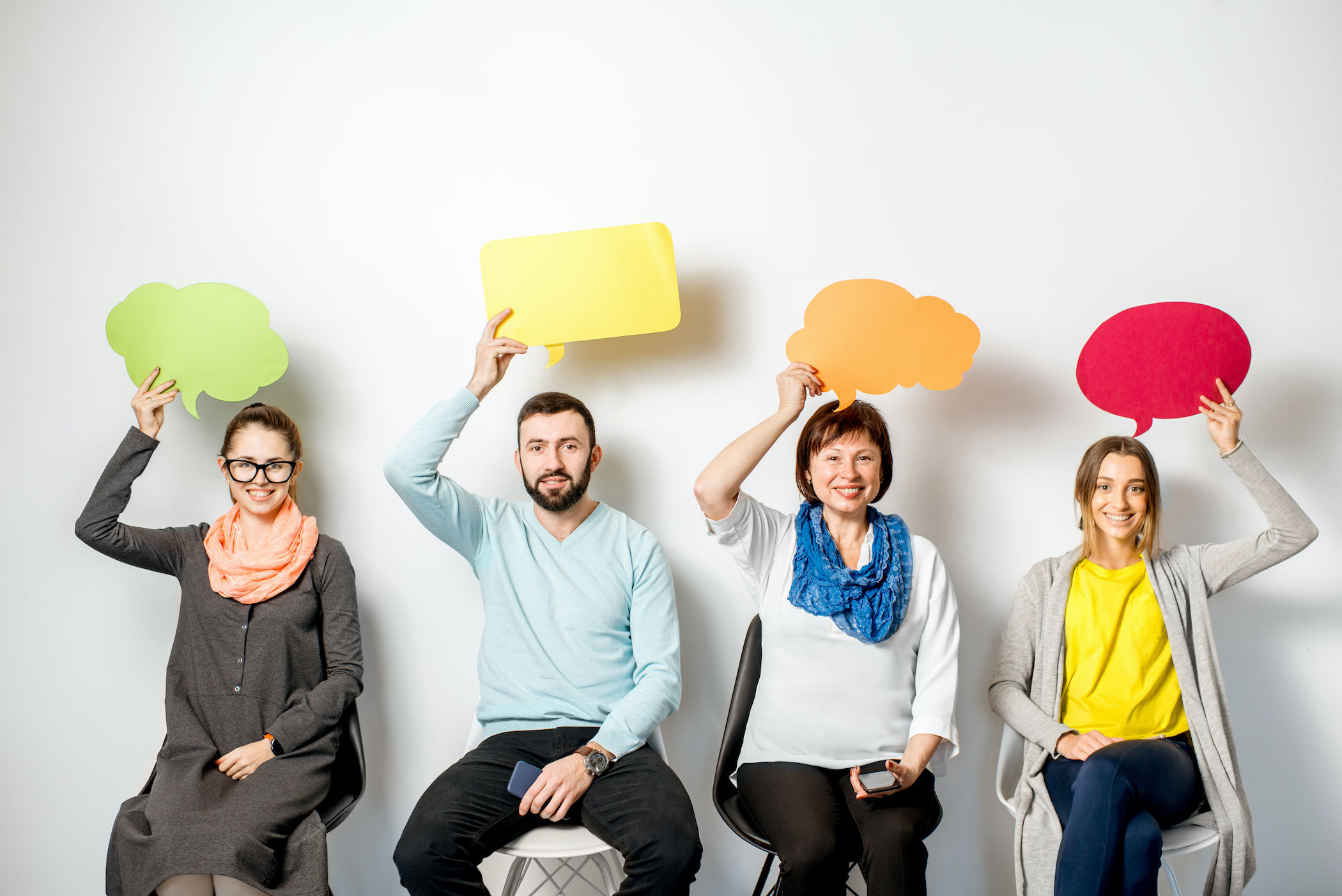 men and women holding thought bubbles over head