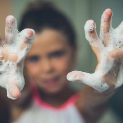 child holding up soap sud covered hands