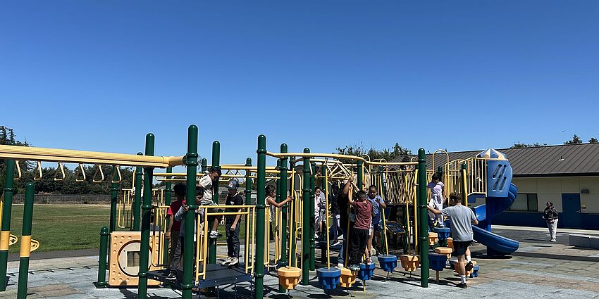 Children playing on a play structure at a school playground.