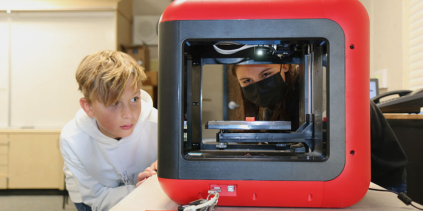 students looking at a 3-D printer