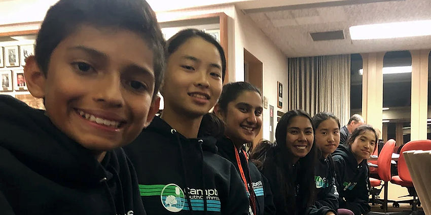 girls and boys sitting in a row and smiling at the camera