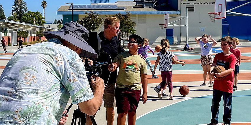 children on playground with cameraman and film director