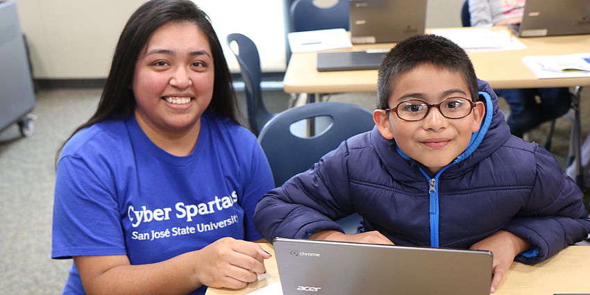 college student works with young boy at computer