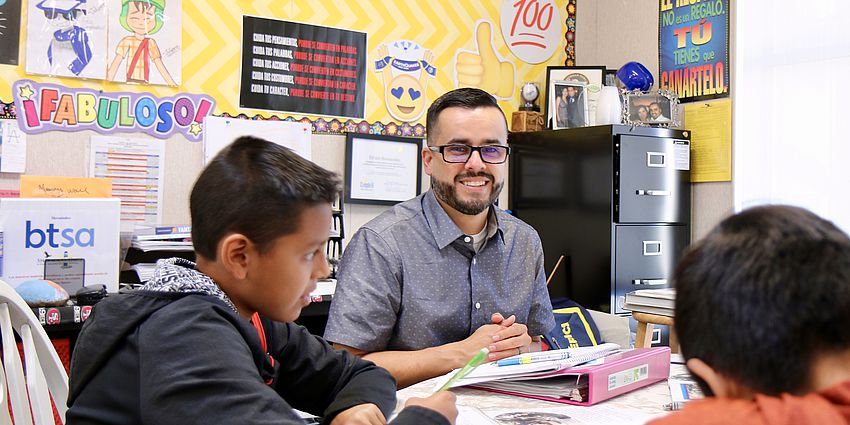 male teacher smiling with students at table