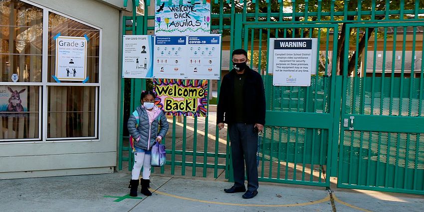 student and principal stand at gate to school