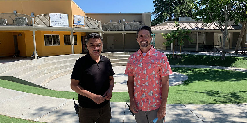 two men standing outside school, smiling