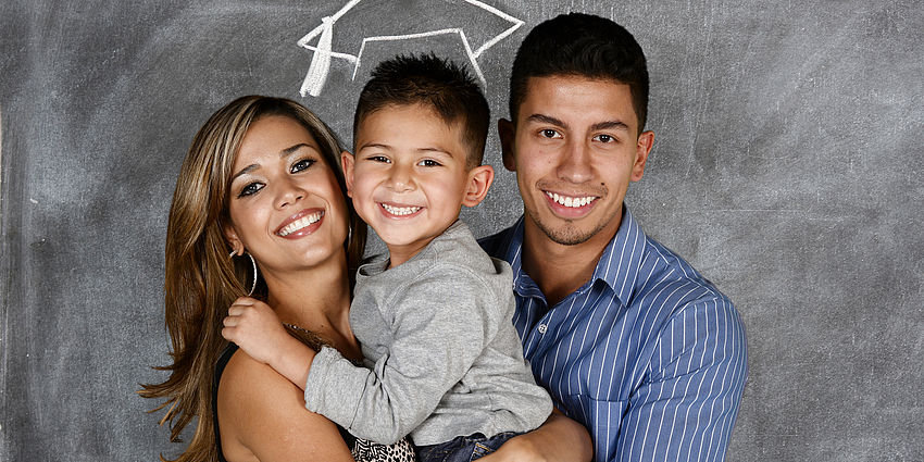 parents hold child with a graduation cap drawn above child's head