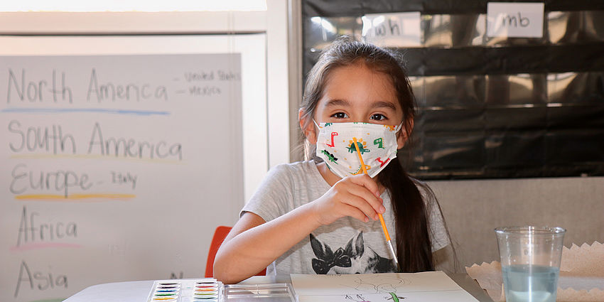 girl in mask with paint and paper