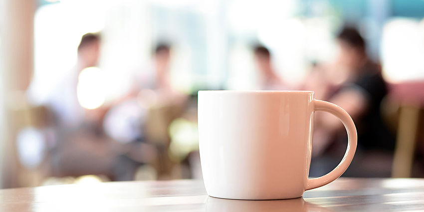 Coffee cup with people meeting in the background