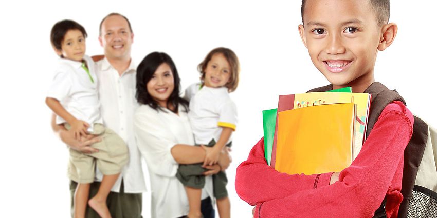 Student holding school supplies and parents in the background