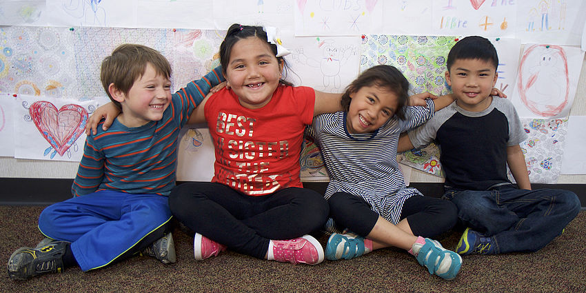 smiling group of kids sitting with arms around each other