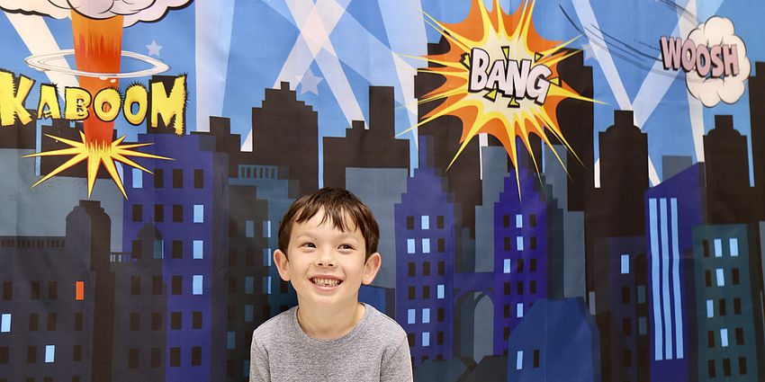 little boy standing by painting of skyscrapers and fireworks