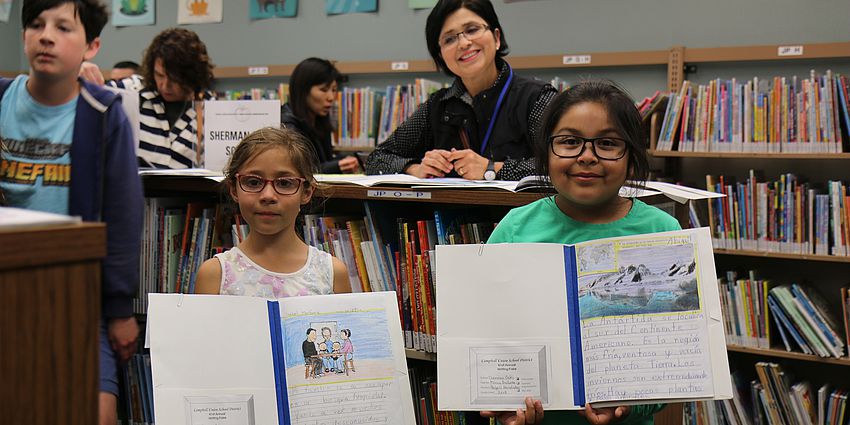 students showing books and smiling