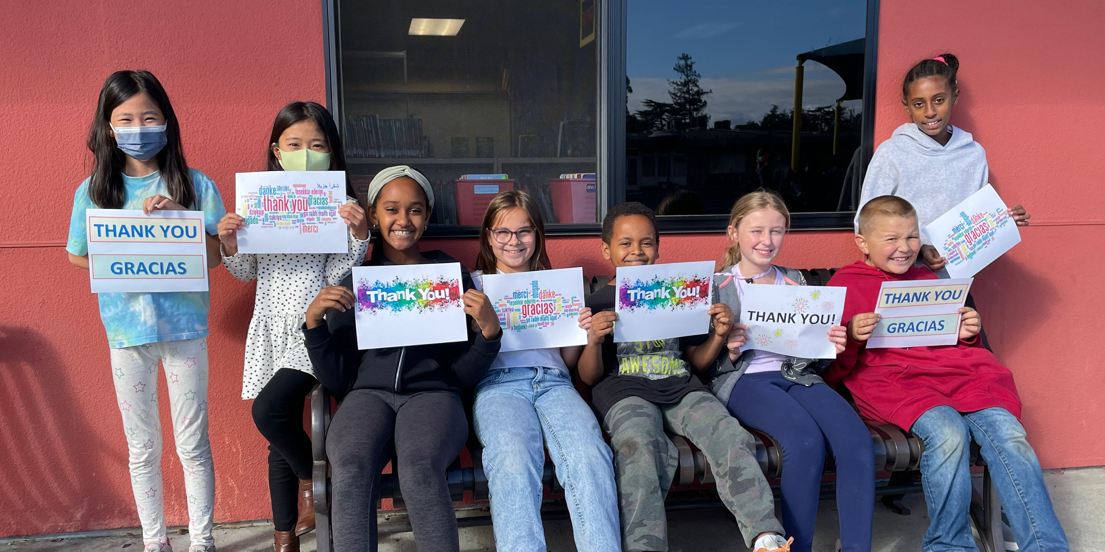 smiling students holding signs that say thank you